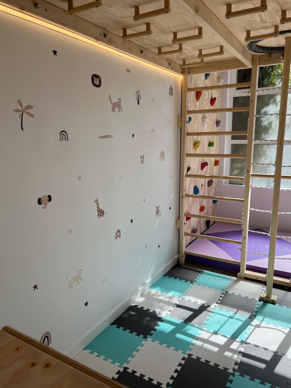 Sala de terapia infantil con estructura de madera y alfombras de colores